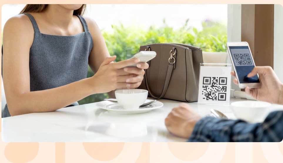 Guest using a mobile payment and QR menu at a cafe table